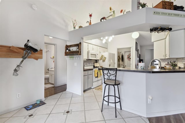 kitchen with white cabinetry, a high ceiling, white appliances, decorative backsplash, and light tile patterned floors