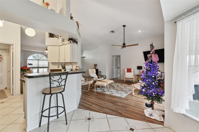 kitchen with kitchen peninsula, tasteful backsplash, ceiling fan, white cabinetry, and light tile patterned flooring