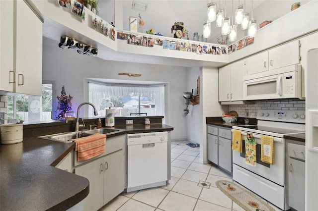 kitchen featuring hanging light fixtures, white cabinets, backsplash, white appliances, and light tile patterned floors