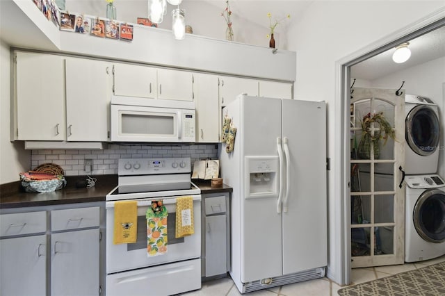 kitchen with white appliances, white cabinets, decorative backsplash, light tile patterned floors, and stacked washer / drying machine