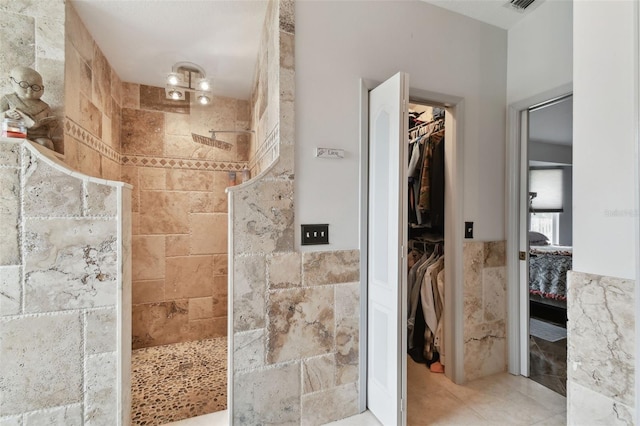 bathroom with a tile shower and tile walls