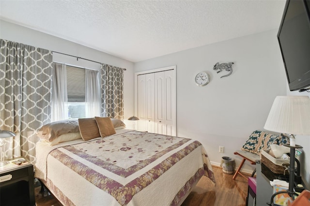 bedroom with a closet, wood-type flooring, and a textured ceiling