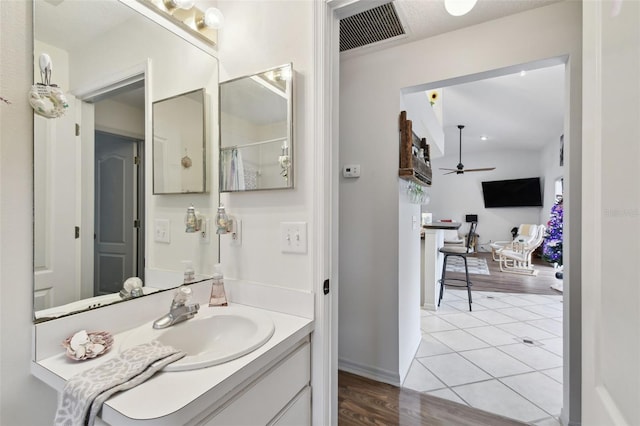 bathroom with wood-type flooring, vanity, ceiling fan, and curtained shower