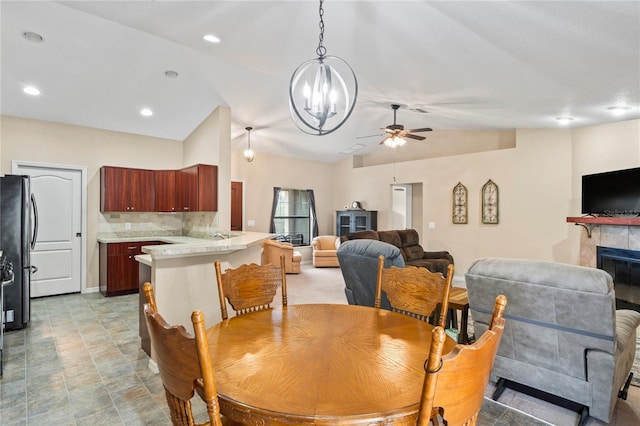 dining space featuring lofted ceiling, ceiling fan, and a tile fireplace