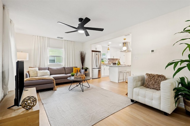 living room featuring ceiling fan and light hardwood / wood-style flooring