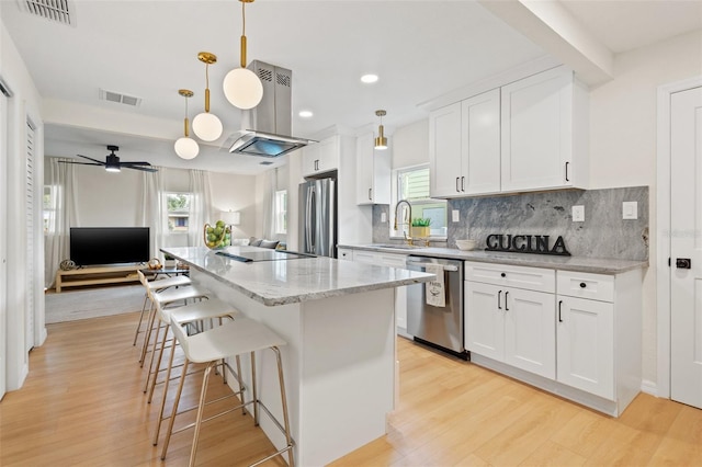 kitchen with pendant lighting, white cabinets, stainless steel appliances, and a kitchen island