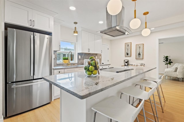 kitchen featuring white cabinets, pendant lighting, stainless steel refrigerator, and sink