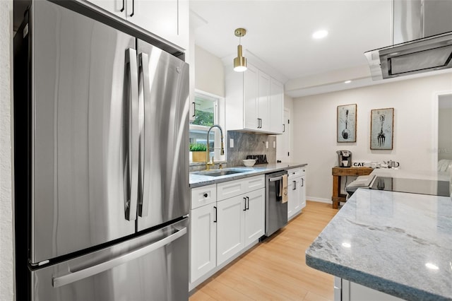 kitchen with sink, light stone counters, pendant lighting, white cabinets, and appliances with stainless steel finishes