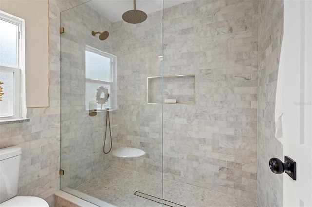 bathroom with a tile shower, tile walls, and toilet