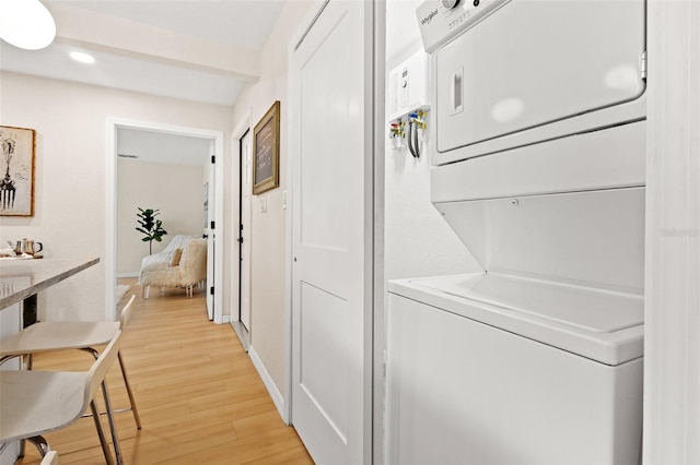 laundry area featuring stacked washer and dryer and light hardwood / wood-style floors