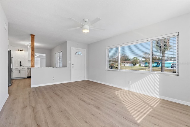 unfurnished living room with light hardwood / wood-style floors, ceiling fan, and sink