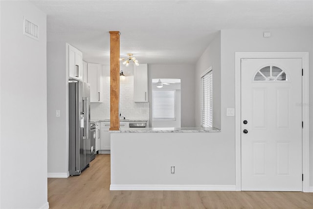 kitchen featuring backsplash, light hardwood / wood-style flooring, ceiling fan, high quality fridge, and white cabinetry