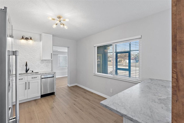 kitchen with light stone countertops, stainless steel appliances, white cabinetry, and light hardwood / wood-style floors