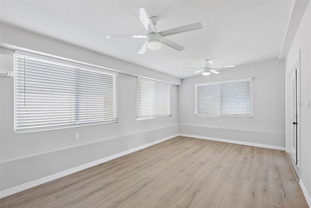 empty room featuring a textured ceiling, light hardwood / wood-style floors, and ceiling fan