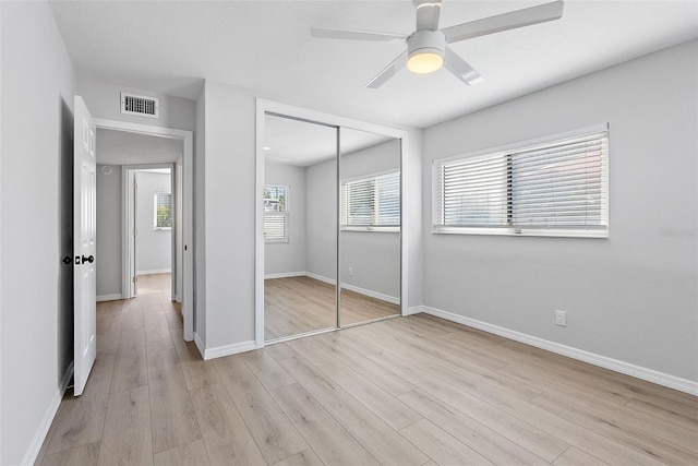 unfurnished bedroom featuring ceiling fan, a closet, and light wood-type flooring