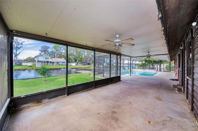 unfurnished sunroom featuring ceiling fan and a water view