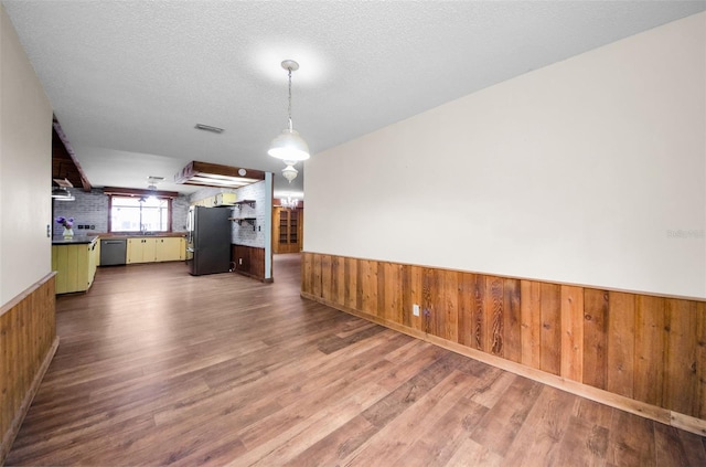 unfurnished dining area featuring hardwood / wood-style flooring, wood walls, and a textured ceiling