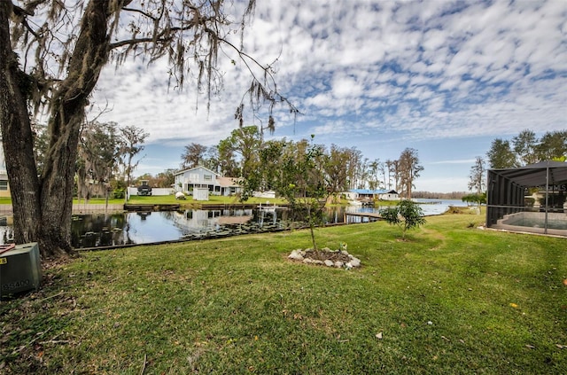 view of yard featuring glass enclosure and a water view