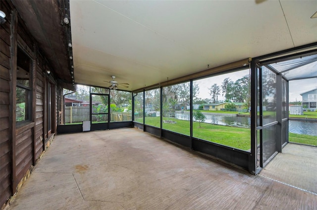 unfurnished sunroom featuring a water view, ceiling fan, and a healthy amount of sunlight