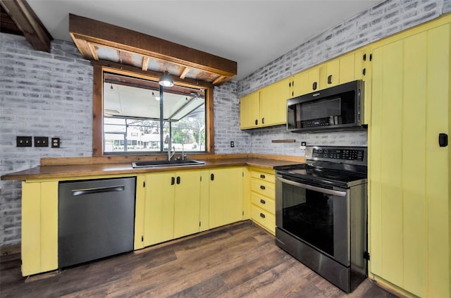 kitchen featuring appliances with stainless steel finishes, brick wall, sink, beamed ceiling, and dark hardwood / wood-style floors