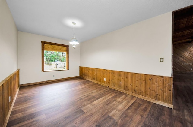 spare room featuring dark wood-type flooring and wood walls