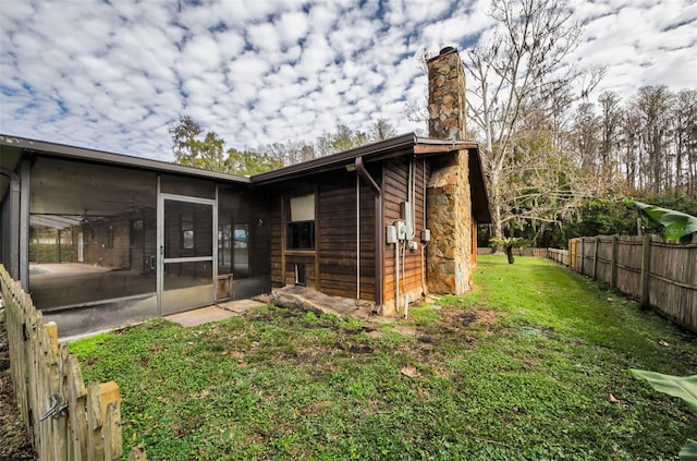 back of property featuring a lawn and a sunroom