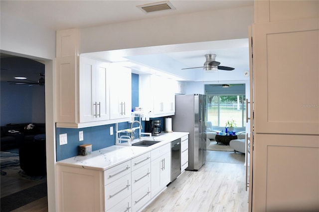 kitchen with stainless steel appliances, ceiling fan, sink, light hardwood / wood-style flooring, and white cabinetry