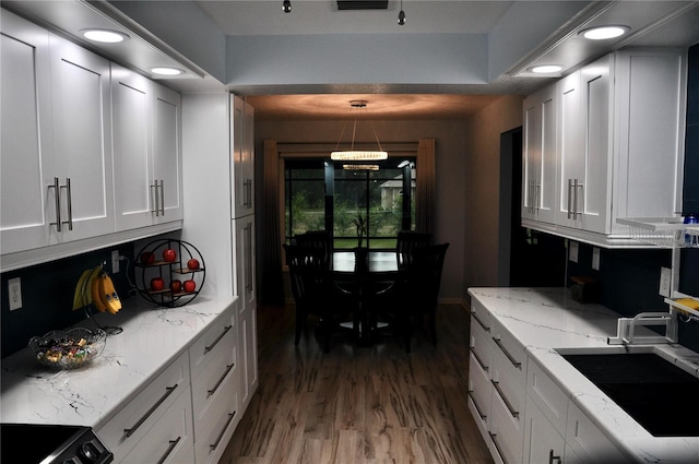 kitchen with light stone countertops, sink, dark hardwood / wood-style floors, white cabinetry, and hanging light fixtures