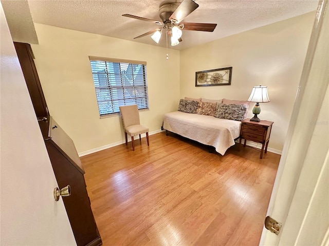 bedroom featuring ceiling fan, light hardwood / wood-style floors, and a textured ceiling