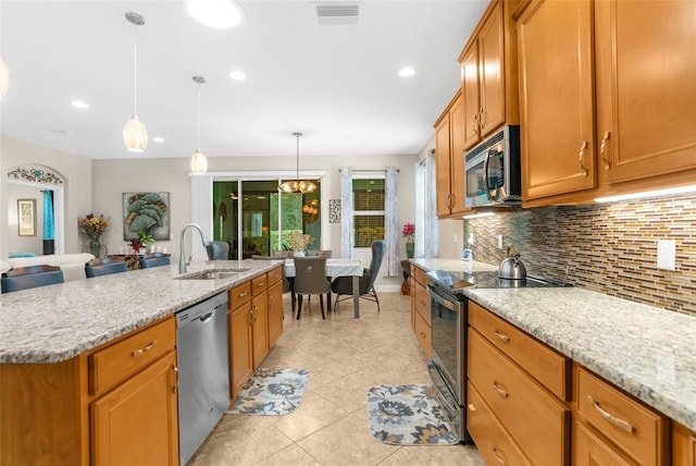 kitchen with a kitchen island with sink, sink, decorative backsplash, decorative light fixtures, and stainless steel appliances