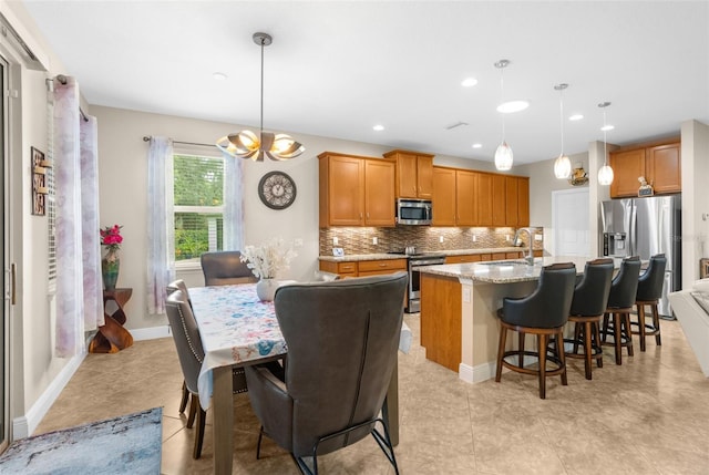 kitchen featuring pendant lighting, sink, stainless steel appliances, and an island with sink