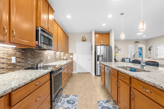 kitchen with sink, decorative backsplash, light stone countertops, appliances with stainless steel finishes, and decorative light fixtures