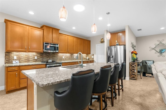 kitchen with appliances with stainless steel finishes, a kitchen island with sink, pendant lighting, and sink