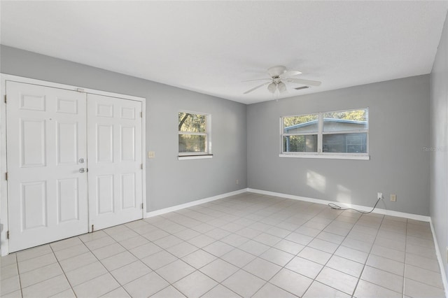 unfurnished bedroom with ceiling fan, light tile patterned flooring, and a closet