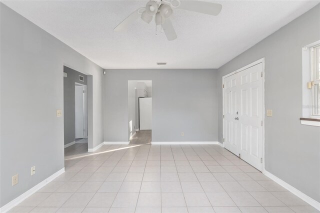 tiled spare room with ceiling fan and a textured ceiling