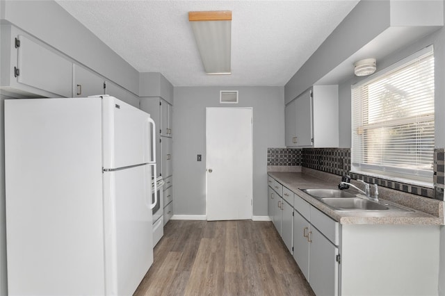 kitchen with white fridge, sink, white cabinetry, and a textured ceiling