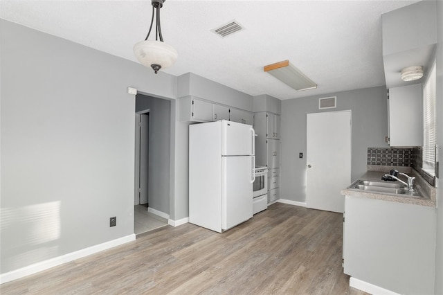 kitchen featuring stove, tasteful backsplash, sink, pendant lighting, and white refrigerator