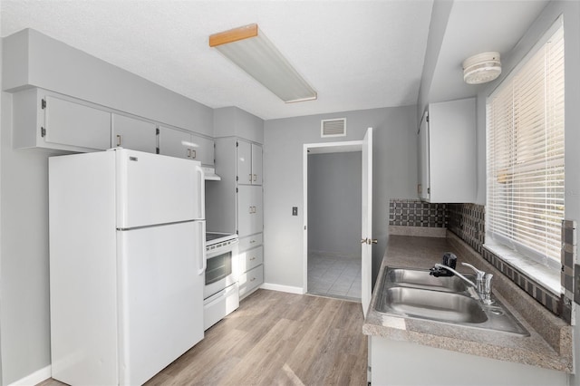 kitchen featuring ventilation hood, white refrigerator, sink, light wood-type flooring, and range