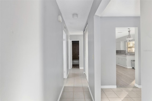 hall featuring light tile patterned floors and sink