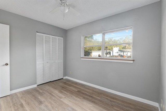 unfurnished bedroom with ceiling fan, a closet, a textured ceiling, and light wood-type flooring