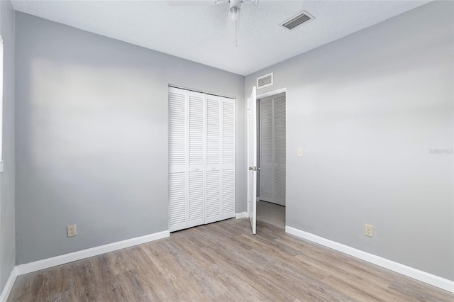 unfurnished bedroom with ceiling fan, a closet, and light wood-type flooring