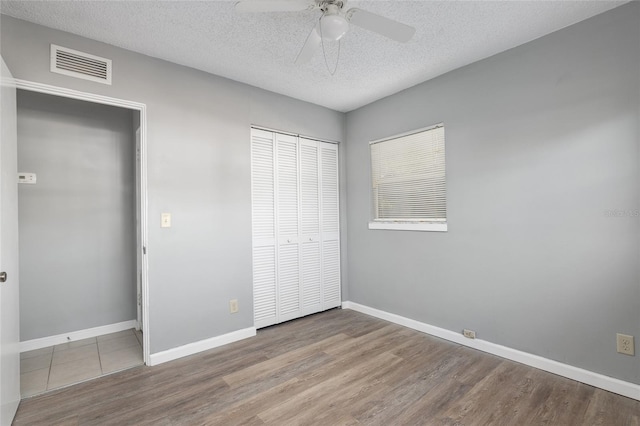 unfurnished bedroom with hardwood / wood-style floors, a textured ceiling, a closet, and ceiling fan