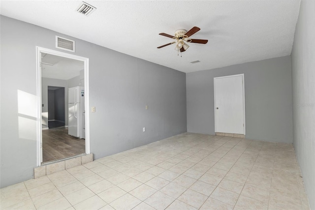 unfurnished room featuring ceiling fan, light tile patterned floors, and a textured ceiling