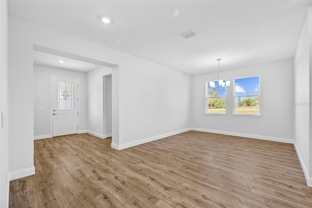 unfurnished room with light hardwood / wood-style floors and an inviting chandelier