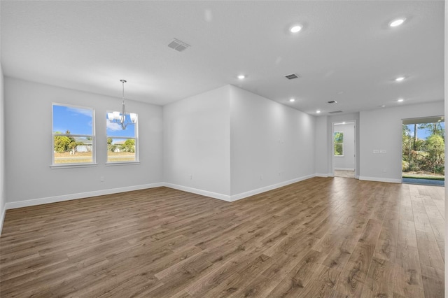 unfurnished room with a chandelier and wood-type flooring