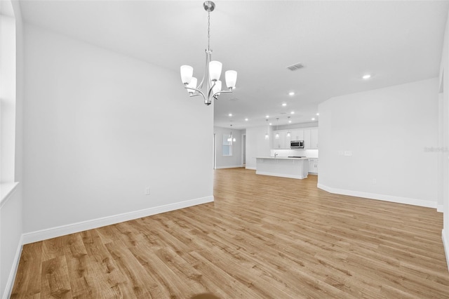 unfurnished living room featuring light hardwood / wood-style floors and an inviting chandelier