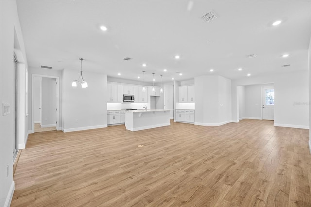 unfurnished living room featuring light hardwood / wood-style flooring and a notable chandelier