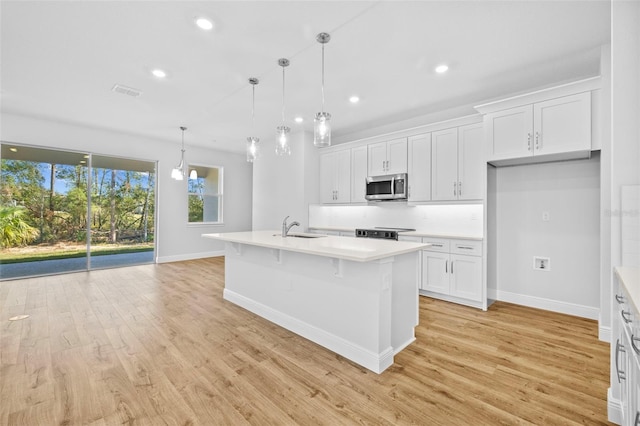 kitchen with sink, decorative light fixtures, a center island with sink, white cabinets, and light hardwood / wood-style floors