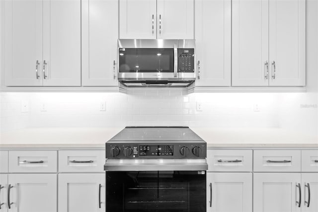 kitchen featuring backsplash, white cabinets, and appliances with stainless steel finishes