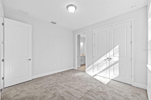 unfurnished bedroom featuring connected bathroom, light carpet, and a closet